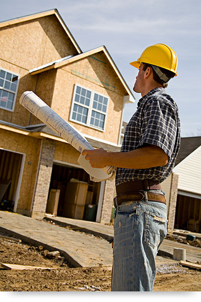 Contractor standing by house with floorplans1